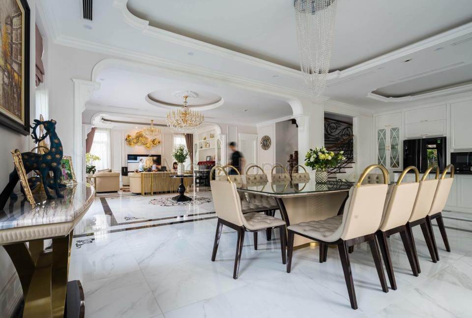 Phong cách tân cổ điển được thể hiện bởi lối thiết kế phào chỉ, đèn chùm, bộ bàn ghế ấn tượng, kệ decor gỗ tự nhiên,...